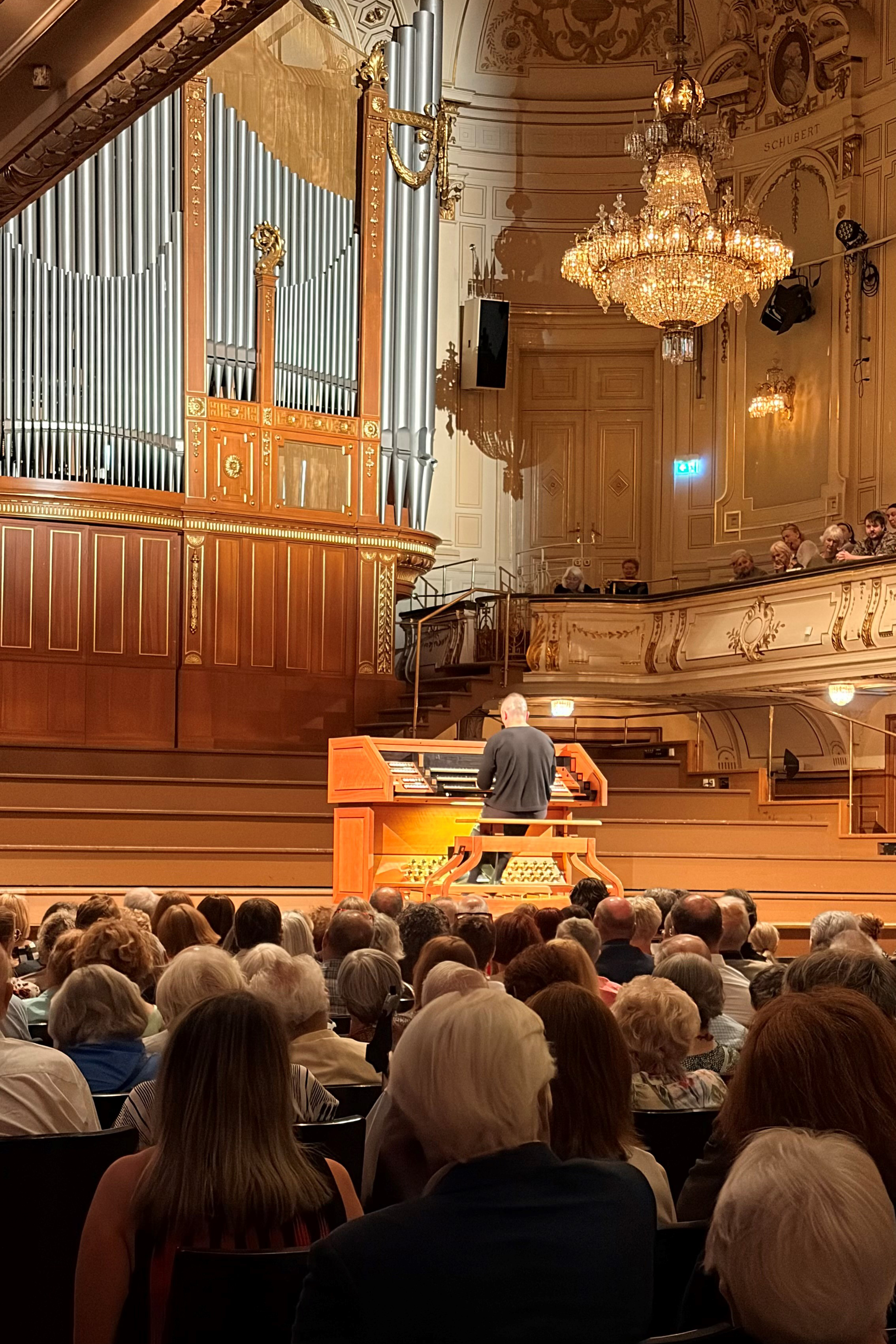 Organist spielt auf einem großen Orgelinstrument vor einem Publikum in einem Konzertsaal.